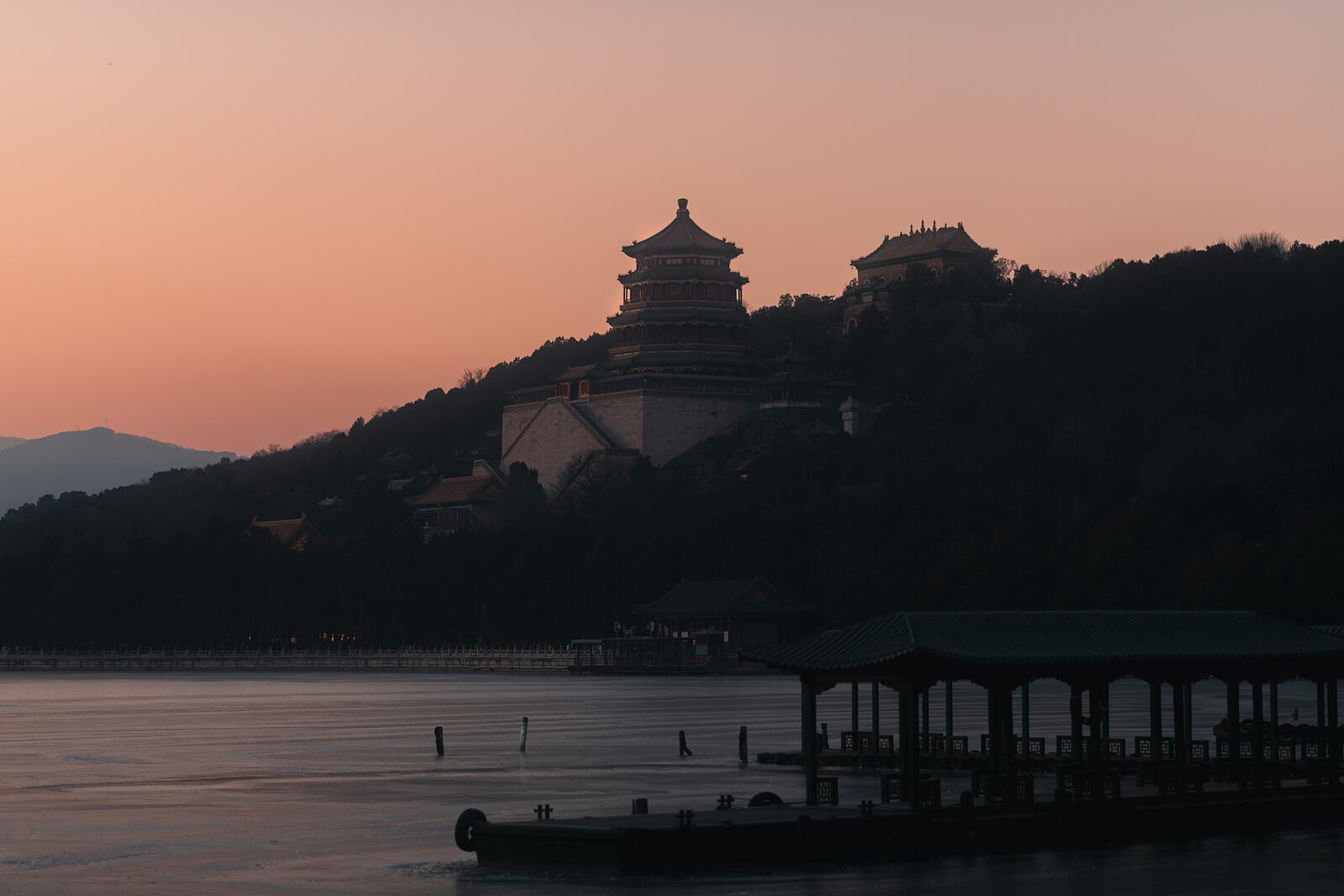 The Tower of Buddhist Incense rising over Longevity Hill against a soft pink dusk, a covered lakeside pavilion below