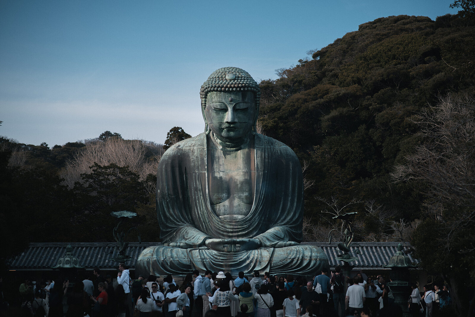 The Great Buddha of Kamakura, with a crowd gathered at its base in fading dusk light